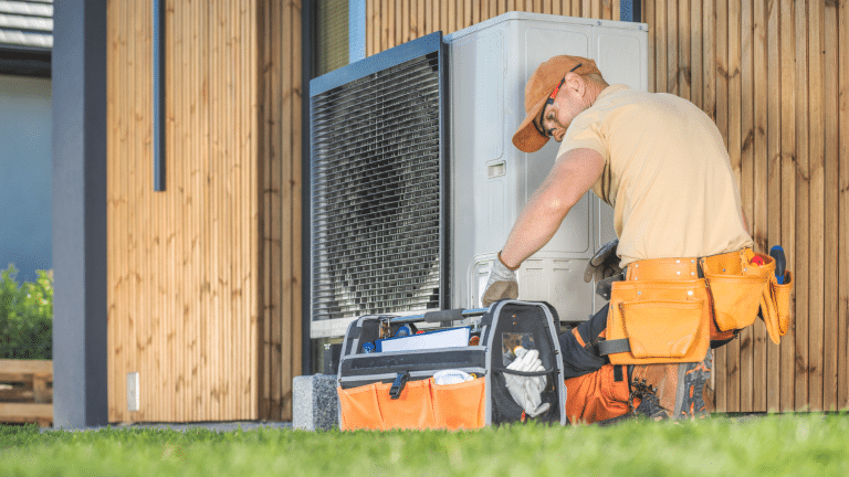 HVAC technician working on outdoor unit with tool bag — representing home service professionals in need of HVAC lead generation solutions.